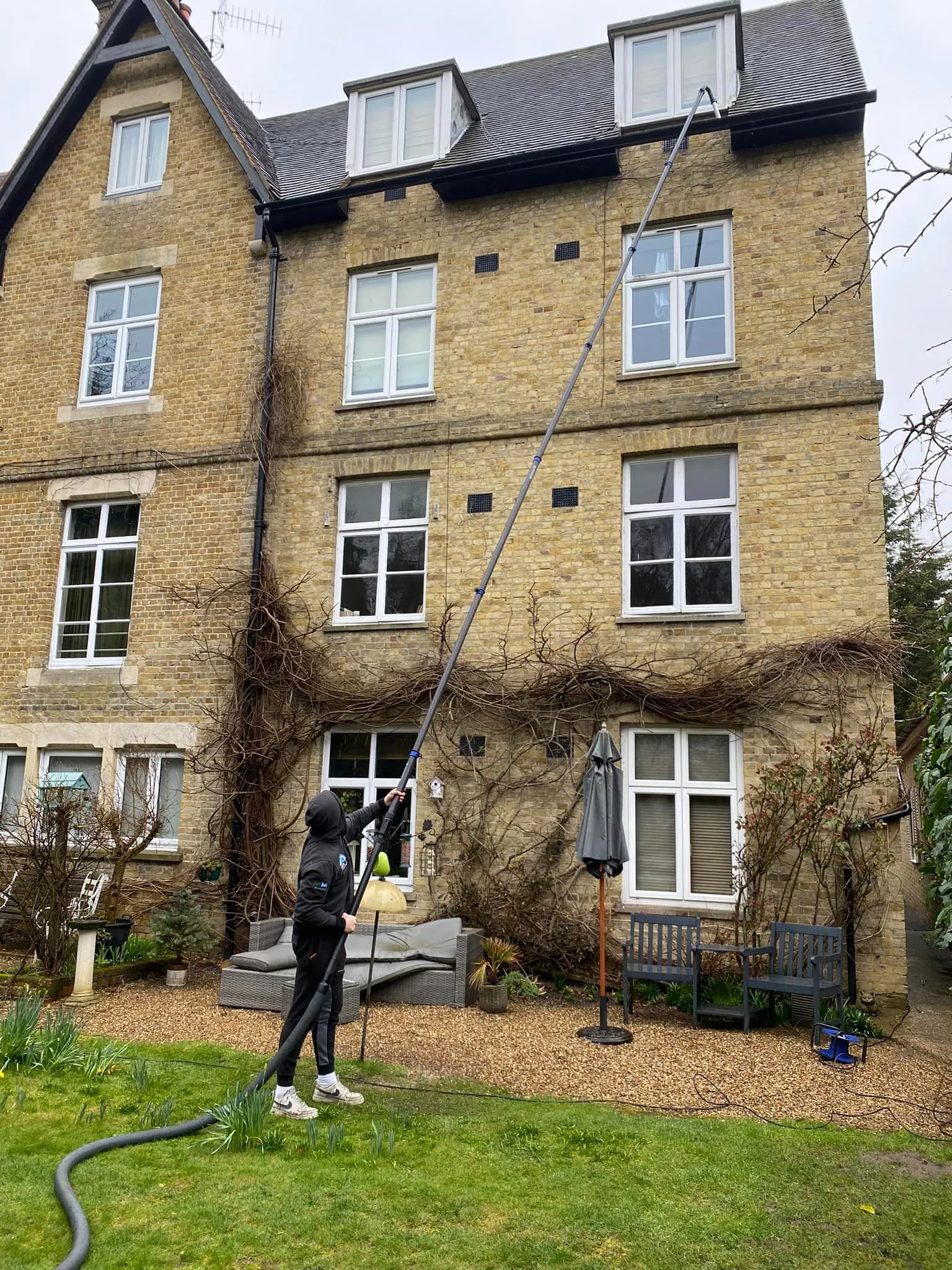 A man with a hose in front of a house.
