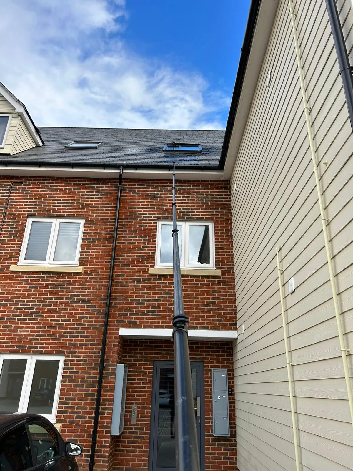 A black car parked in front of a brick building.