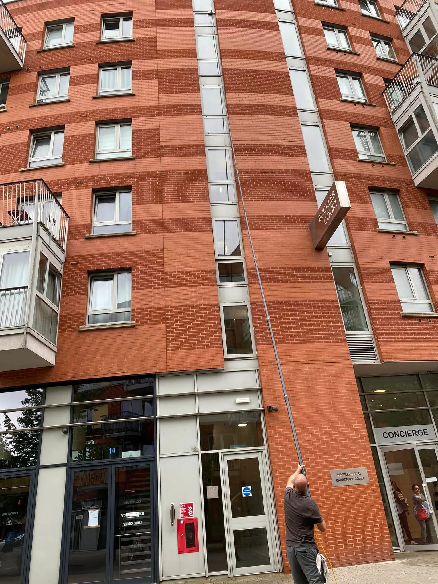 A man standing in front of a tall red brick building.